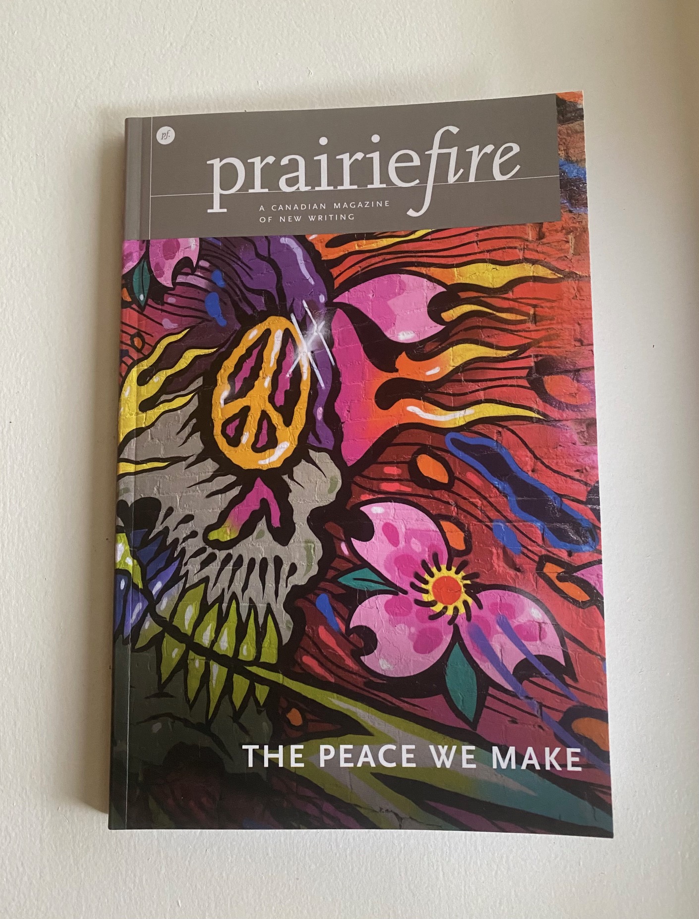 Cover of Prairie Fire Magazine featuring graffiti art with peace symbol and flower